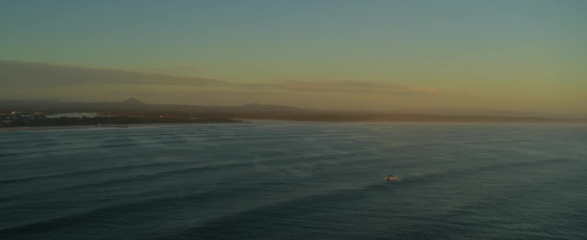 A rubber boat floats in the ocean waves far from shore at dusk