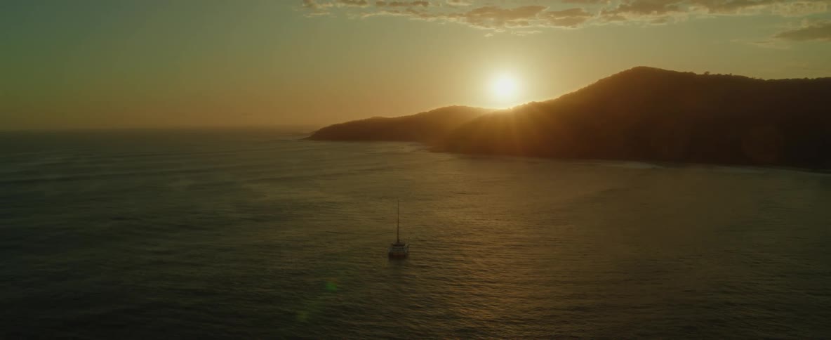 Aerial view of sailboat on open sea at sunset or sunrise