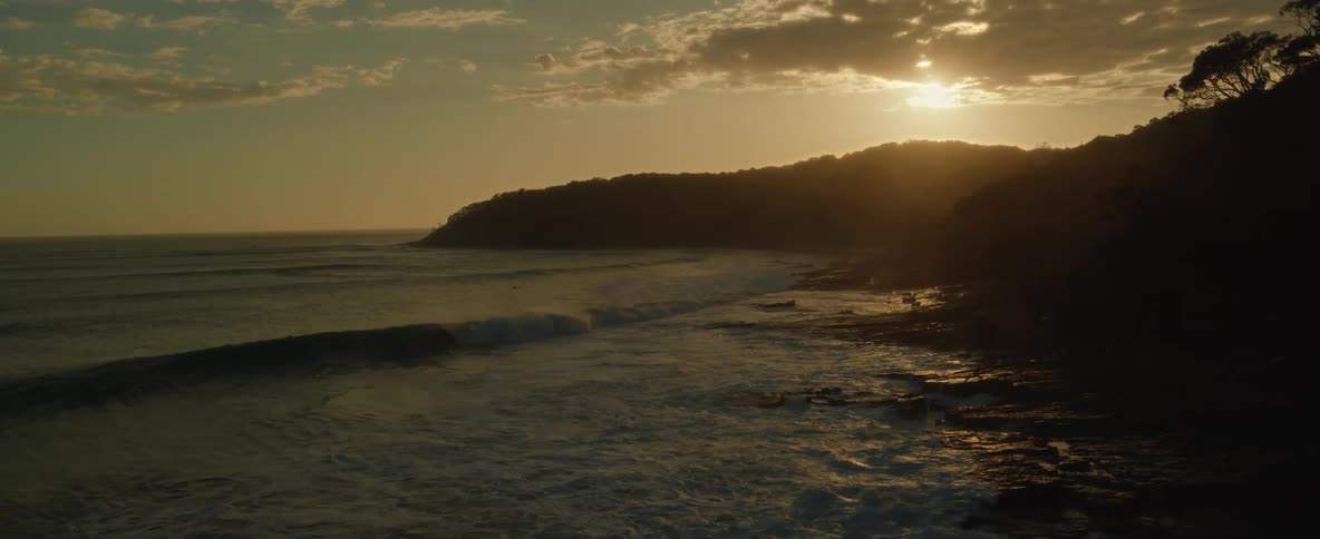 Sun sets over the mountains at the golden hour next to the ocean