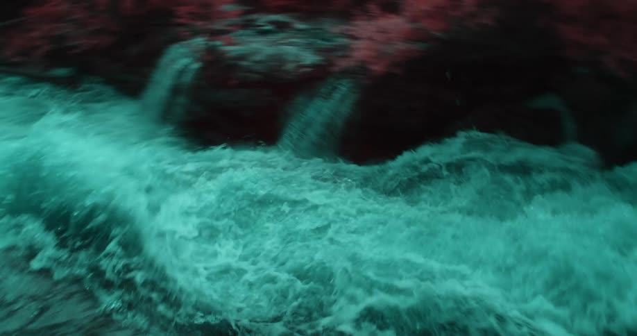 Colored filter tinted whitewater flows through red tinted conifer forest