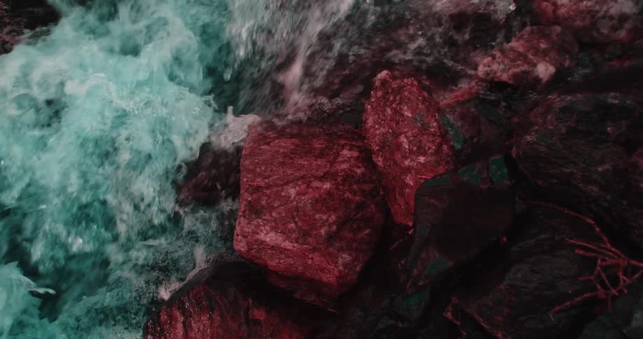 Red tinted boulders contrast with white churning river water