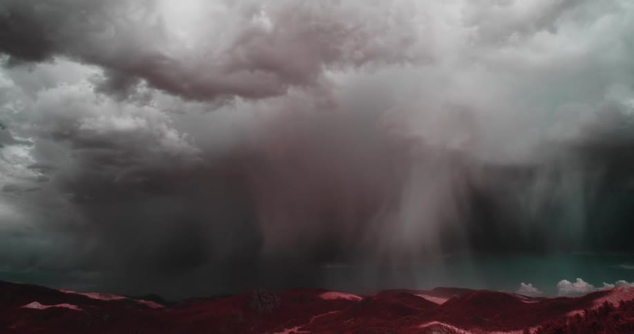Storm clouds cast shadows against red tinted hills