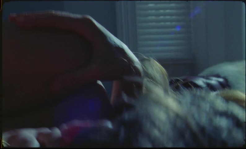 A couple roll around and kiss in a bedroom