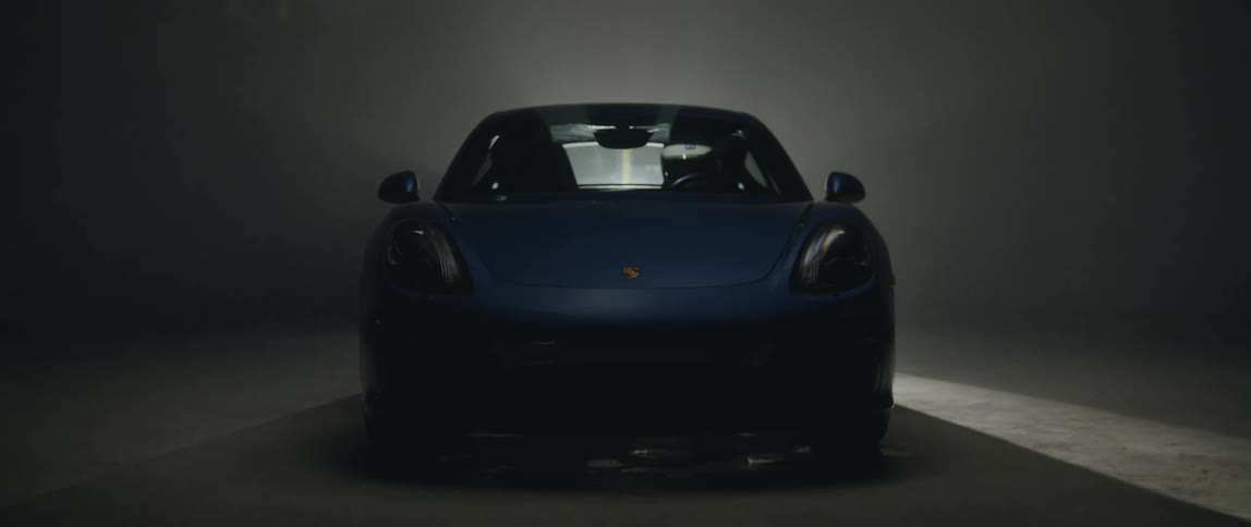 Spotlight rotates through dimly lit area illuminating blue sports car