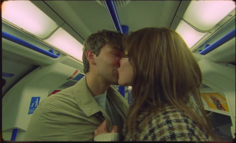 Couple standing in public transport metro car kiss and smile