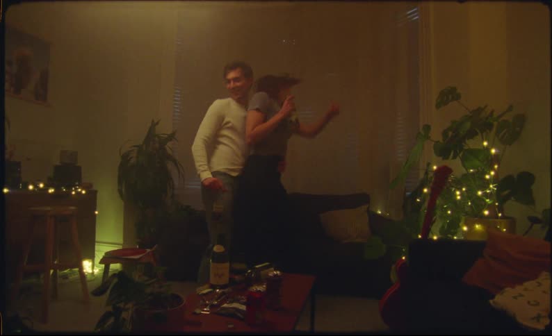 Couple dances energetically in home lit by electric lights