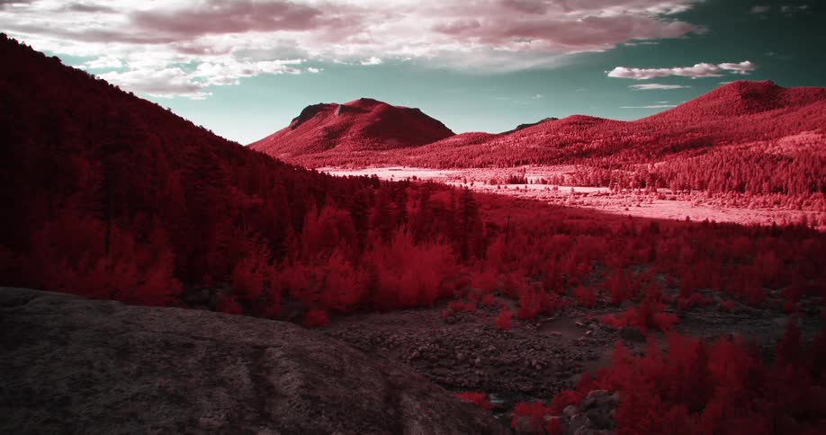 Shadow partly covers red tinted landscape under a blue green sky