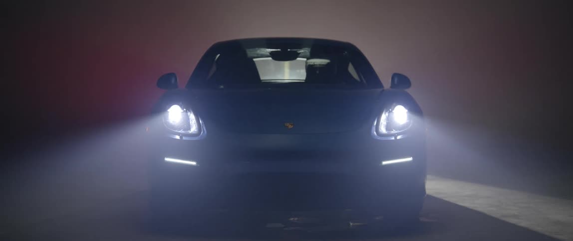 Headlights on sports car come on as spotlight moves across dark area