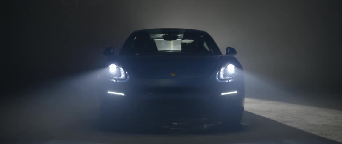 Rotating spotlight illuminates blue sports cars as its lights turn on