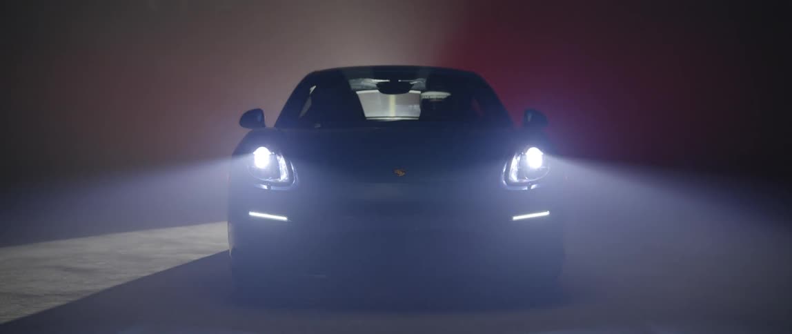 A parked car with its headlights on in a dark place with a moving taillight