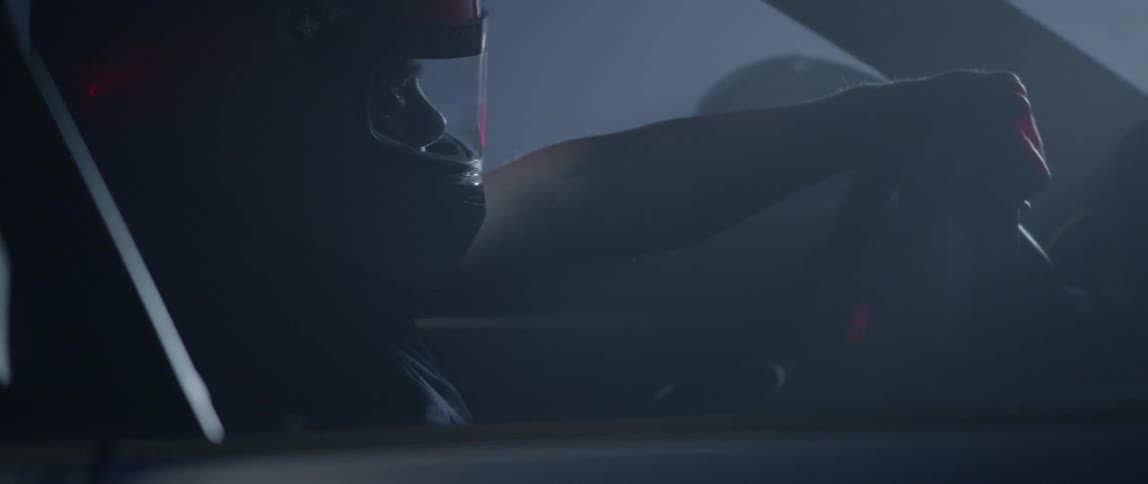 A person wearing a helmet is shown close up driving a racecar super fast