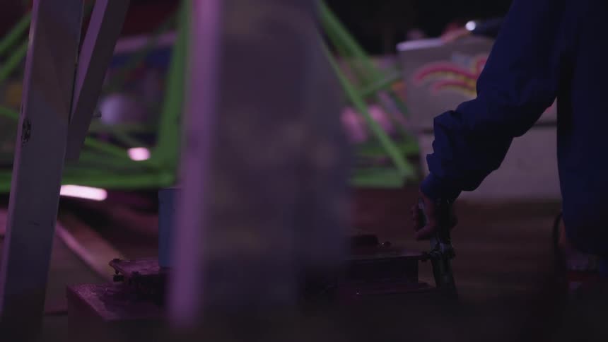 A person controlling an amusement park ride at night
