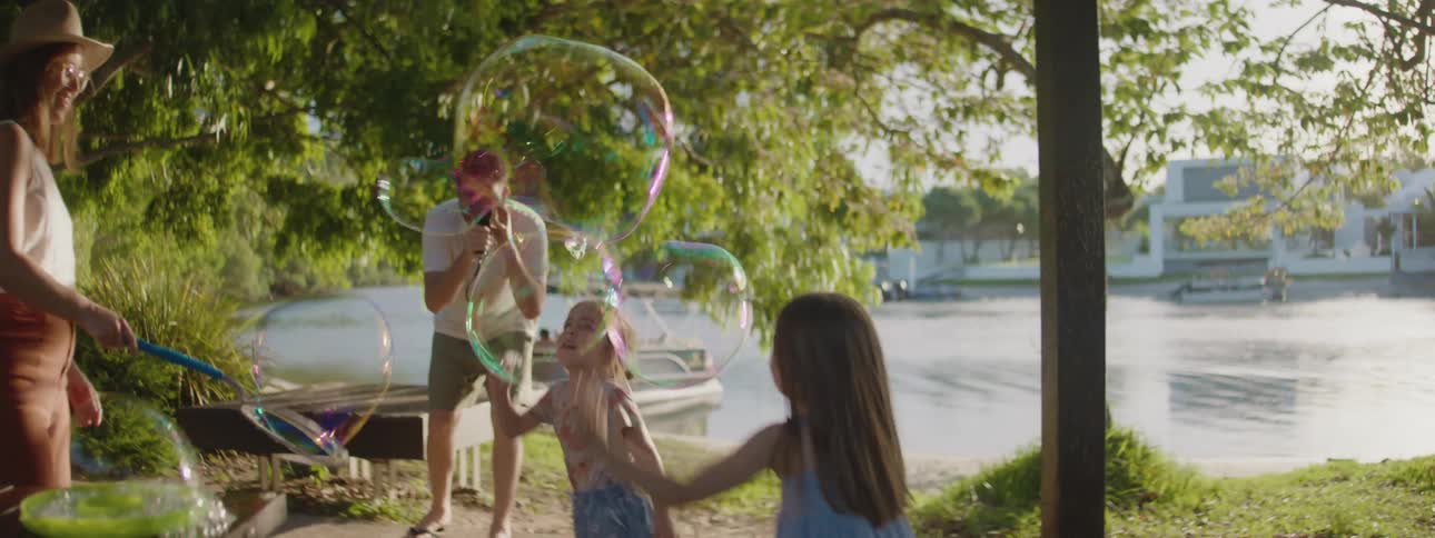 A mother and father playing with bubbles with their kids