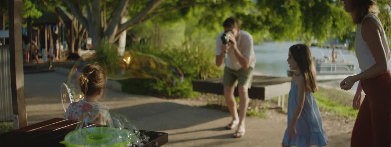Children play with bubbles as their father films