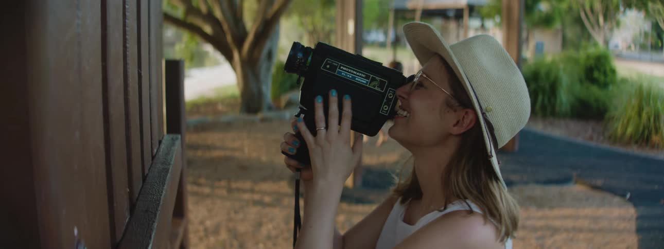 A woman smiles as she holds a video camera as she captures some footage