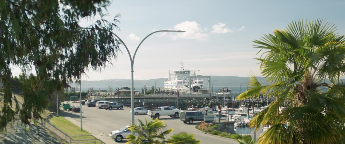 Ferry docked in a pier next to the yachts in the marina in front of a parking lot