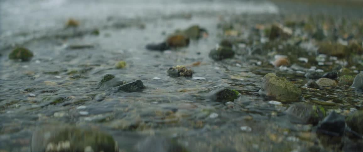 Clear ocean waves roll into a gravel beach