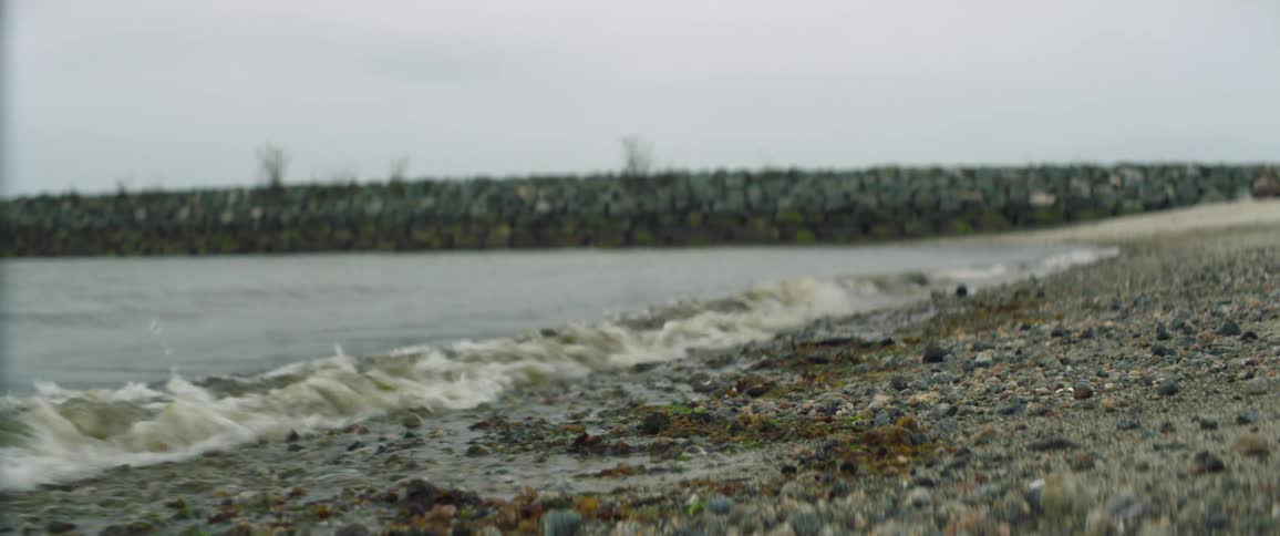 Small sea waves break against coast on a cloudy day