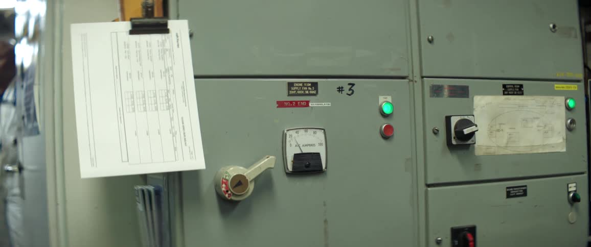 A machine with buttons a lever and a gauge with a note on it with a person standing in the background
