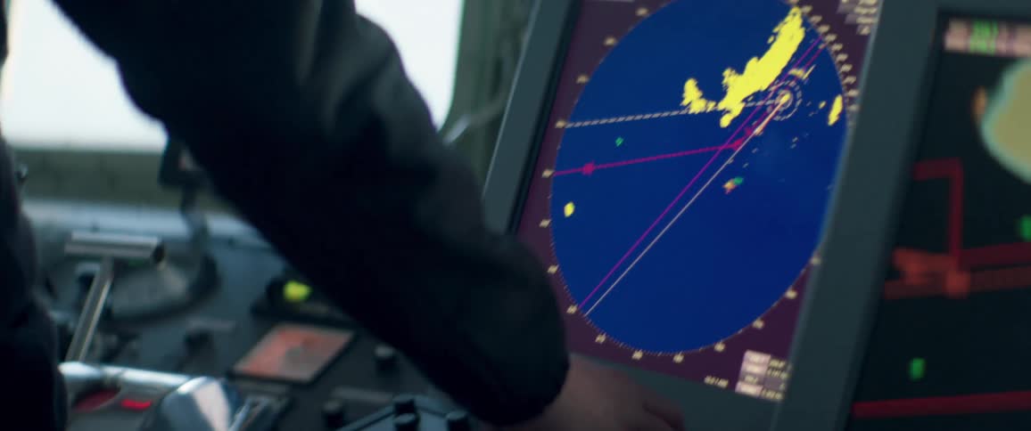 An air traffic control turns a knob and he stands and monitors radar on a screen