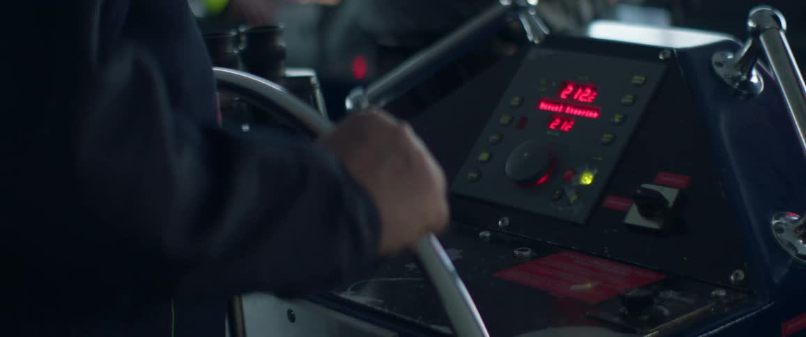 A person is steering the large wheel on the ship
