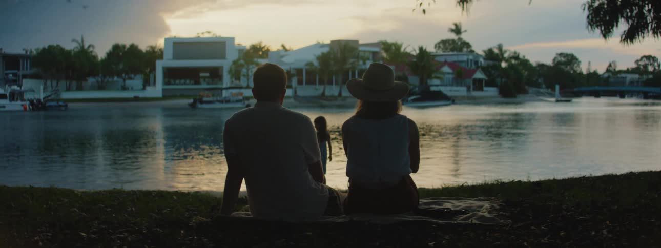 A young couple is sitting down and looking at the view of the lake