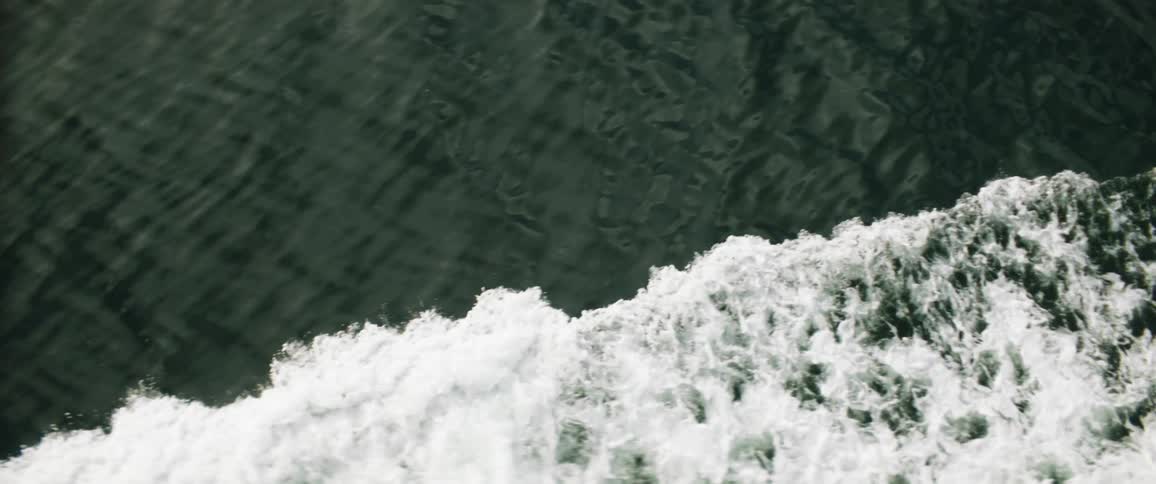 Top down aerial view of a crashing wave rolling over the ocean waters
