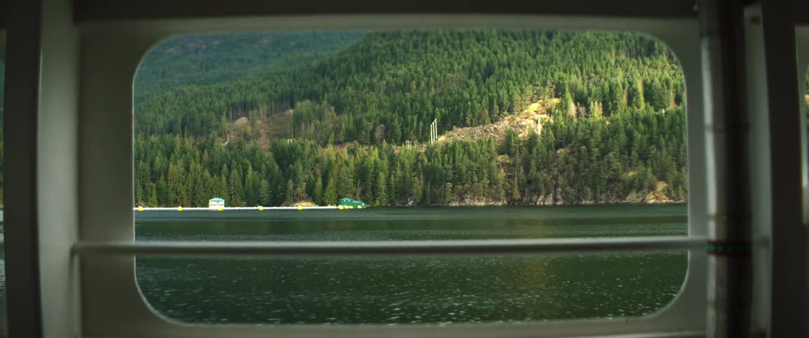 A boat floating on a mountain lake with pine trees on the shore line
