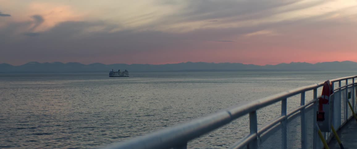 Paralleling ship can be seen over nearby rail as red sky sits on horizon