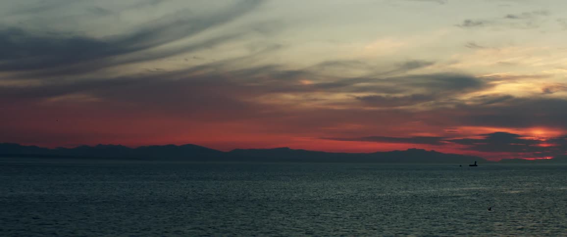 Ripples dance across the surface of the ocean near to a mountainous shoreline
