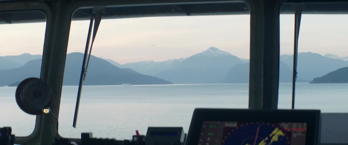 A mountainous coastline shrouded in fog seen from the cockpit of boat just off the coast