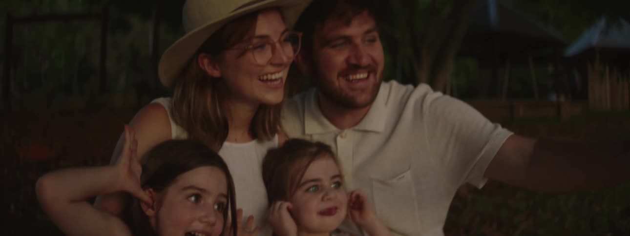 A family of four poses for a selfie as the two daughters make silly faces