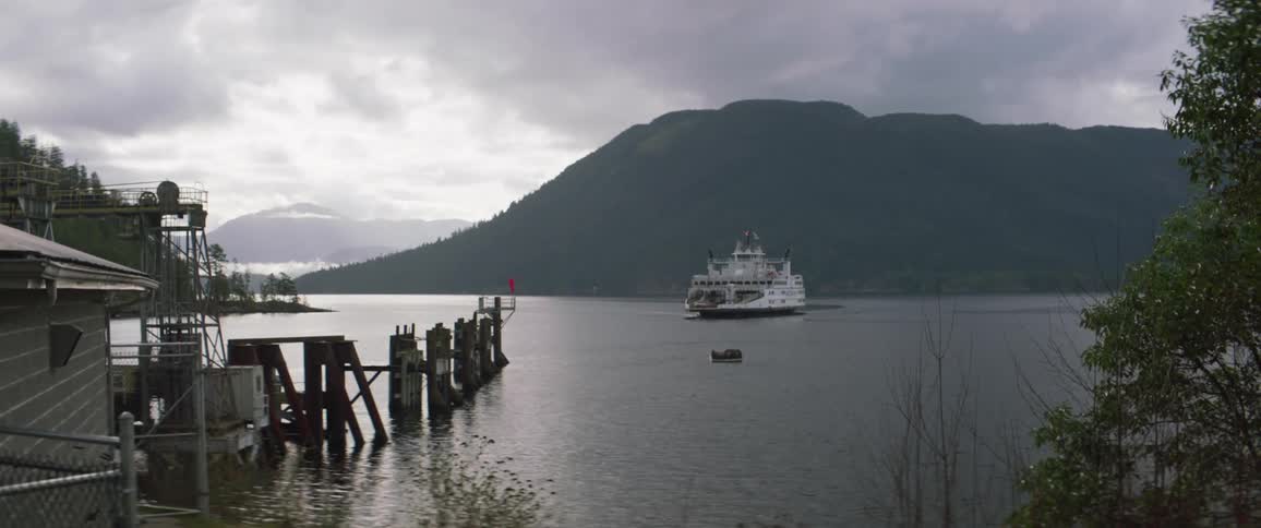 Ferry on a lake next to the mountains heads to a pier