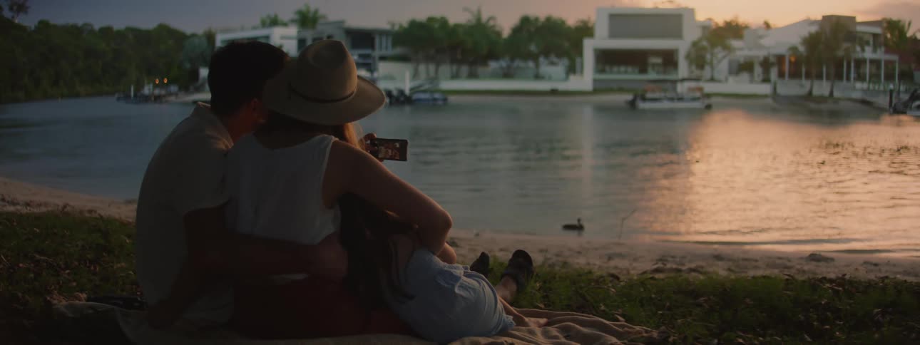 The view is of a young couple sitting down and looking at the water