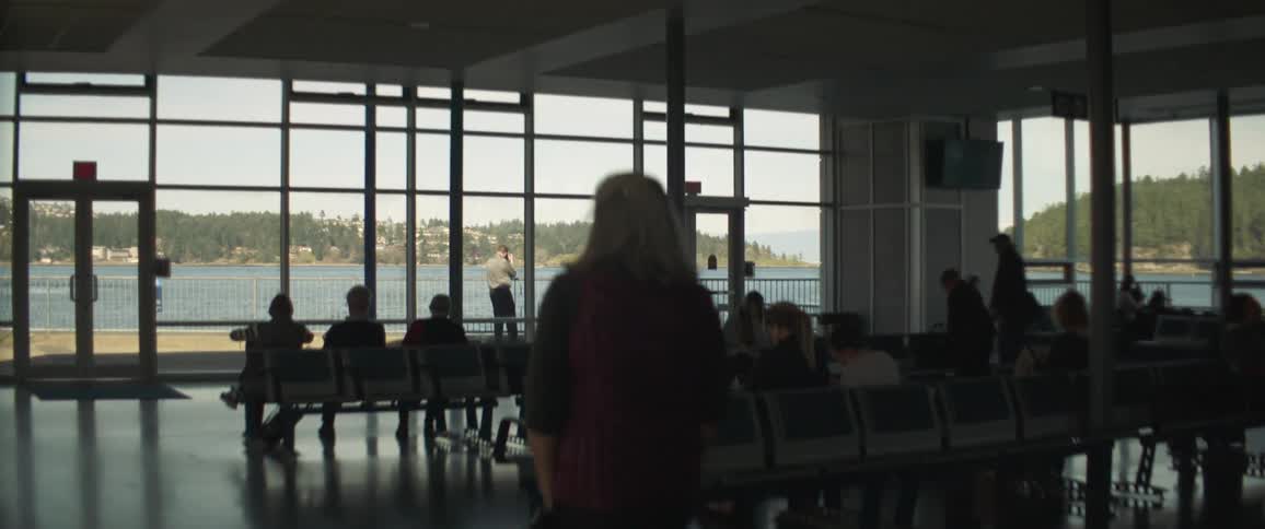 People sitting and walking around a terminal as they wait for a ferry