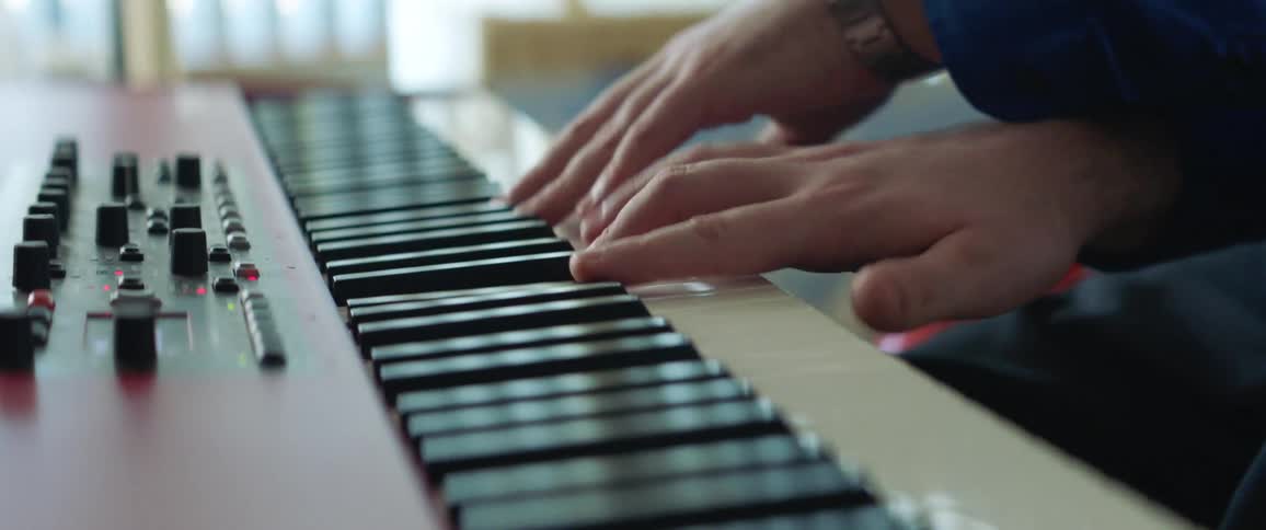A pianist plays a musical keyboard indoors during the day