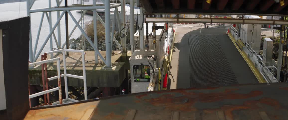 An employee stands in a booth near the water at a shipping port