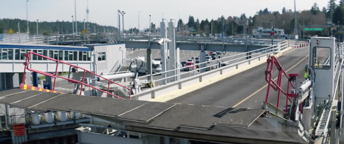 A drawbridge on an overpass slowly raises as a road worker enters the control booth