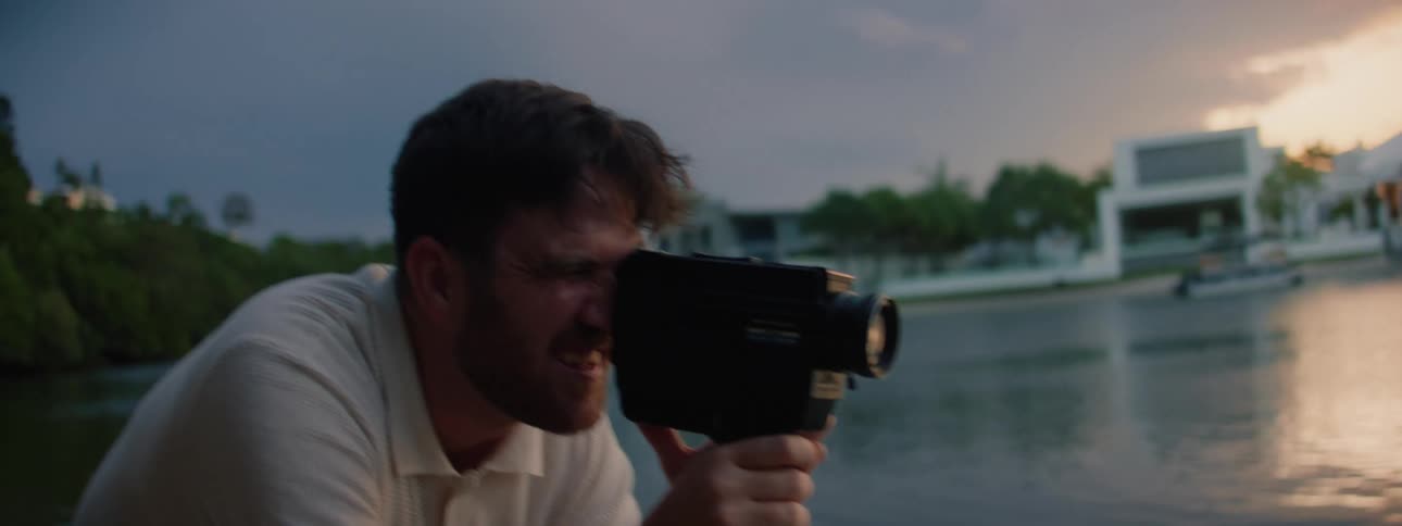 Father films his daughters playing on beach across from woods and town