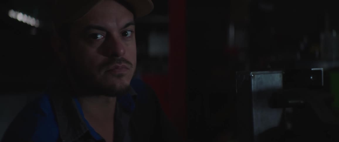 A man is standing by a machine in the dark shop