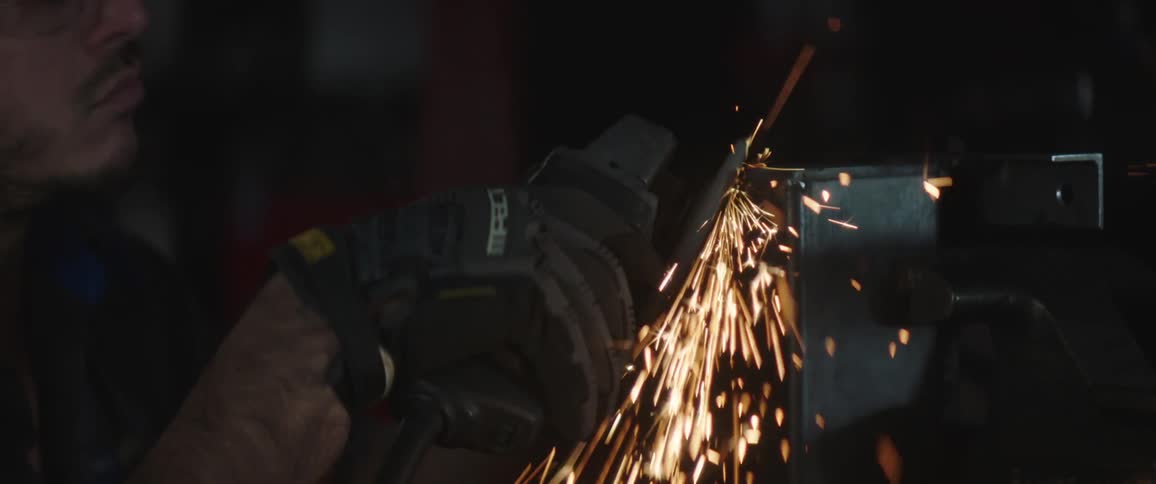 A man is using an angle grinder on a piece of metal