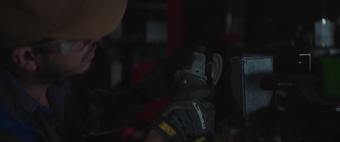 A man is using an angle grinder in the shop