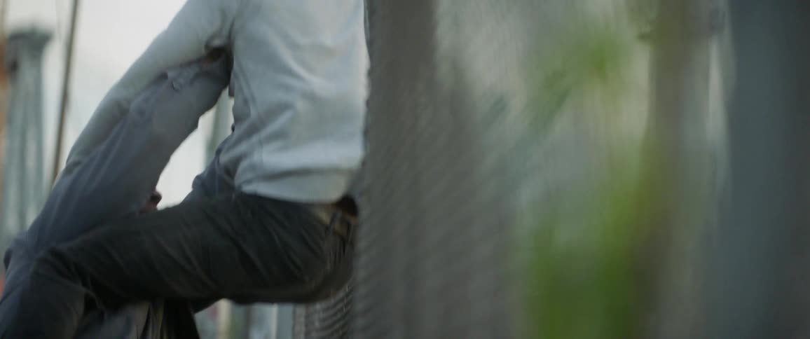 An older man lifts up a younger man and throws him into a fence