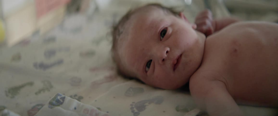 A newborn lies in a bassinet