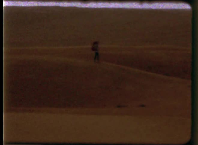 A man hikes over a hill with a backpack