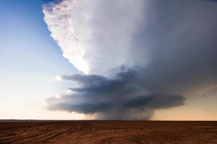 Clouds rolling over a field of dirt