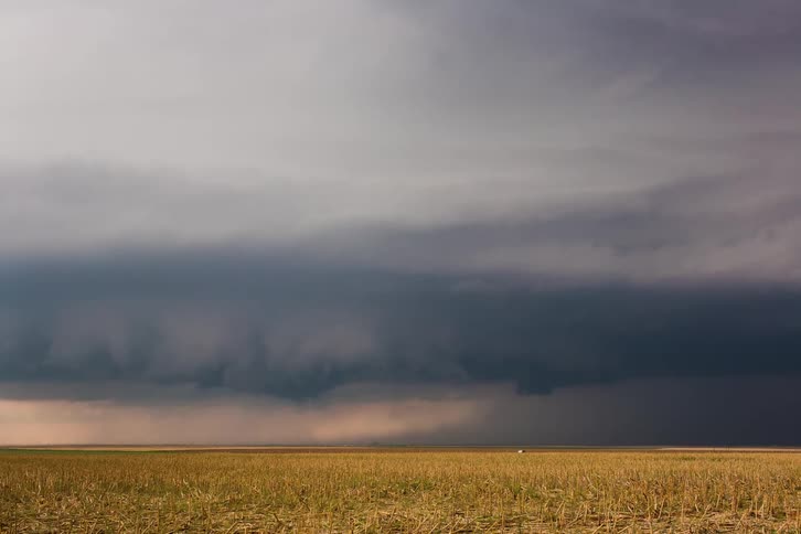 Dark clouds moving over a large empty green field