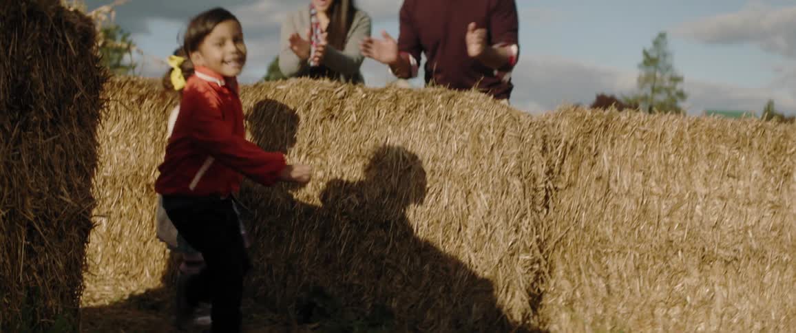 Young children run through a hay maze