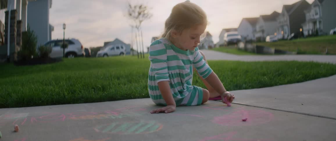 A child is drawing on the sidewalk with chalk