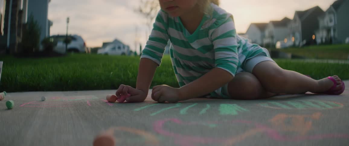 A small child is drawing with sidewalk chalk